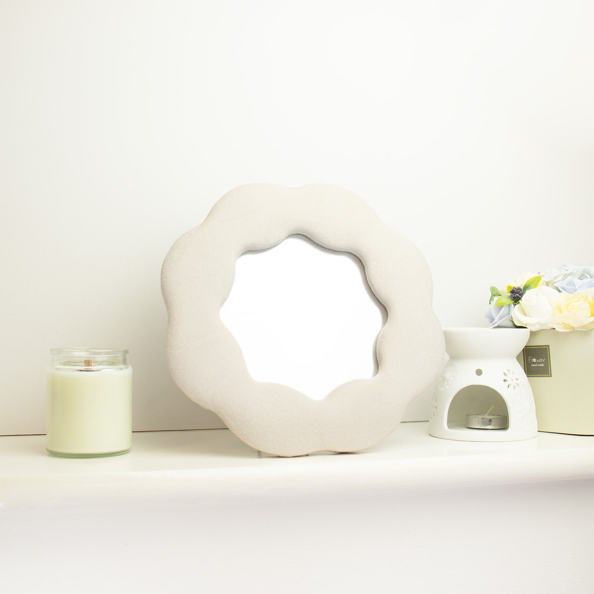 Decorative white wreath with a candle and small plant on a white background