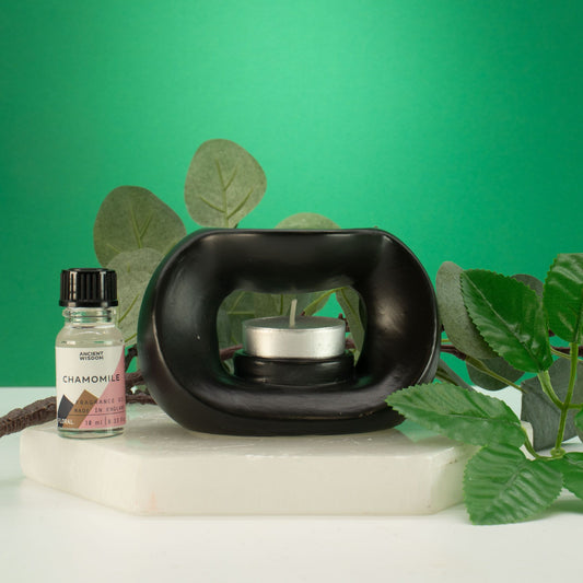Black essential oil diffuser with a bottle of chamomile oil on a green background